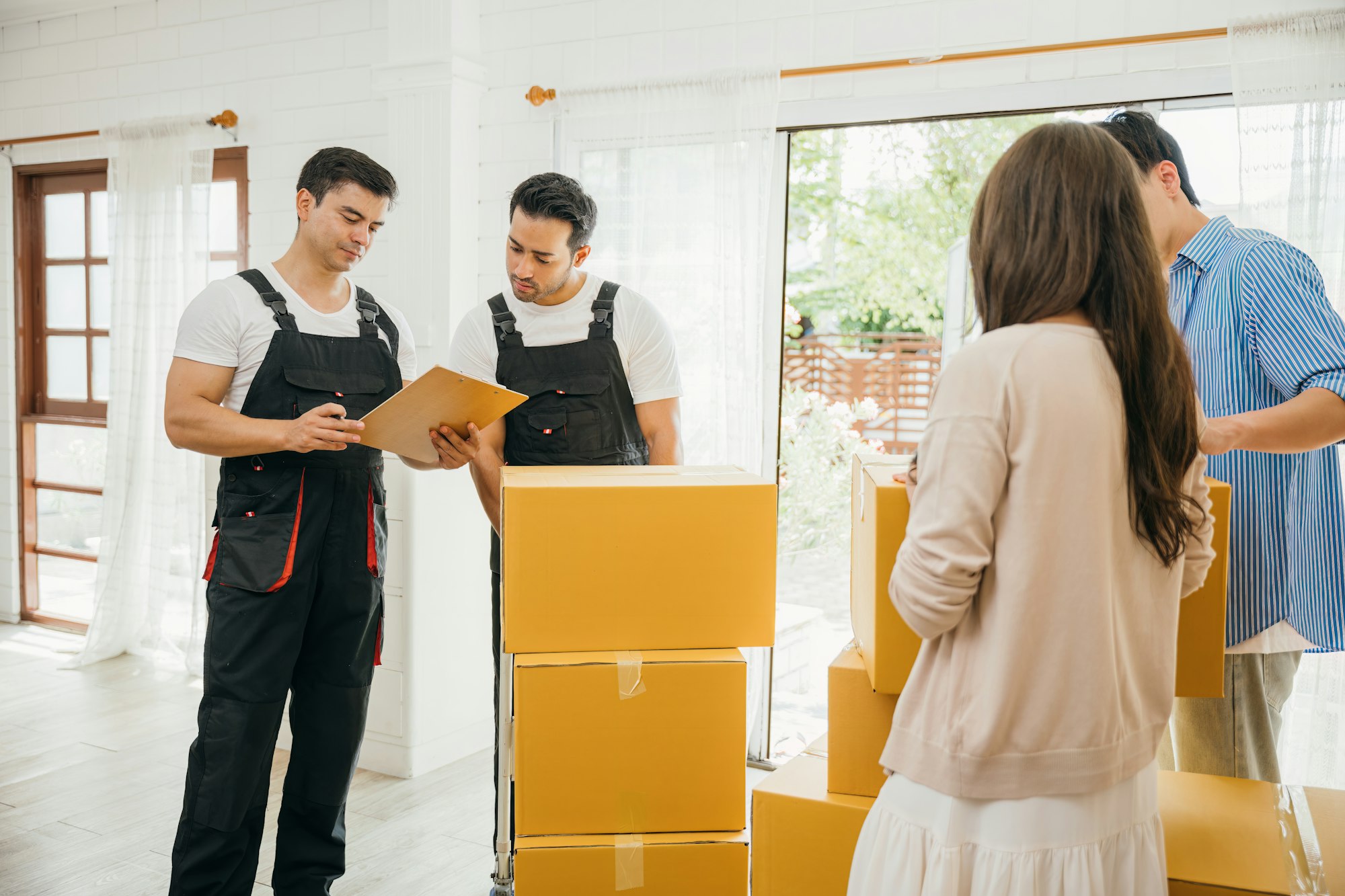 Family examines moving checklist worker holds a box. Professional movers ensure reliable relocation